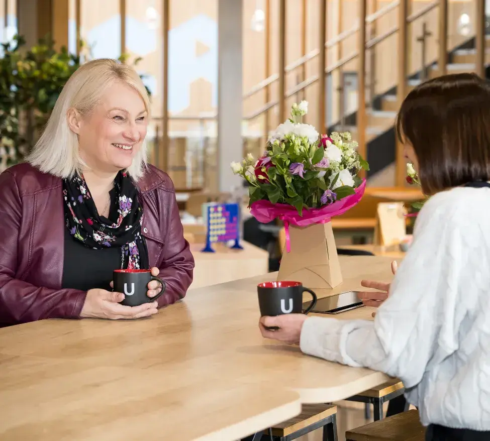 Picture of Claire Watson meeting a client at a coffee shop to chat about their business.